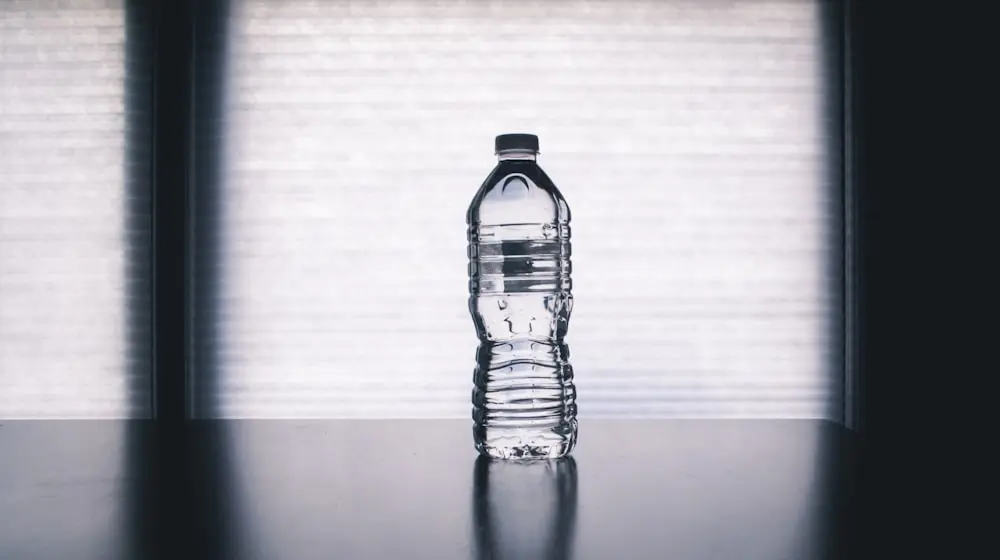 Reusable bottle and notebook beside a sunlit window